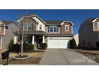 Charming two-story home features a two-car garage, stone accents, and a well-manicured front yard under a clear blue sky at 1100 Wallace Lake Rd, Fort Mill, SC 29707