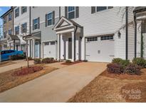 A row of townhomes, each with a one-car garage and covered entrance, showcases modern architecture at 11017 Woodland Creek Way, Charlotte, NC 28262