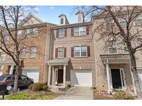 Charming brick townhome featuring a one-car garage and dormer windows under a beautiful blue sky at 14139 Winford Ln, Charlotte, NC 28262