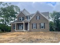Charming two-story brick home featuring a covered front porch and classic architectural details at 2720 Old Course Rd, Monroe, NC 28112
