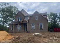 Newly constructed two-story home featuring a brick facade and an inviting front porch at 2720 Old Course Rd, Monroe, NC 28112