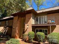 Exterior of a brick condominium building featuring balconies with chairs and green shrubbery in the landscaping at 300 Orchard Trace Ln # 3, Charlotte, NC 28213