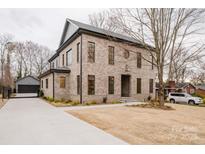 Elegant two-story brick home featuring a driveway leading to a detached garage and a well-maintained front yard at 412 Bertonley Ave, Charlotte, NC 28211