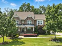 Charming brick home with a covered front porch and beautifully landscaped front yard on a sunny day at 4708 Pearmain Dr, Waxhaw, NC 28173