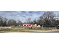 A charming single-story home featuring colorful accents and a playful playground area, secured by a chain-link fence at 224 Bennett St, Charlotte, NC 28213