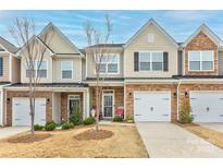 Charming townhome with a one-car garage, brick accents, and a well-manicured lawn in a Gathering-friendly neighborhood at 3941 Rothwood Ln, Harrisburg, NC 28075