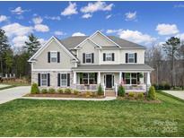 Charming two-story home with a welcoming front porch, a well-manicured lawn, and a mix of stone and siding at 5158 Mill Creek Rd, Clover, SC 29710