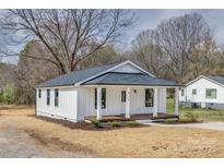 Charming home featuring a covered front porch, white siding, and a dark gray roof at 818 E Charles St, Matthews, NC 28105