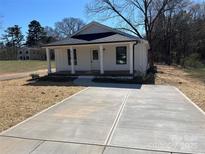 Charming white home with a inviting front porch, newly laid driveway and manicured lawn at 818 E Charles St, Matthews, NC 28105