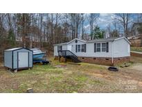 Cozy home featuring vinyl siding, a brick foundation, a useful shed, and convenient front stairs at 109 Dogwood Dr, Hickory, NC 28601