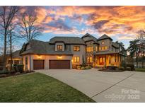 Stately home showcasing a large driveway and a well-manicured lawn during a beautiful sunset at 130 Brick Kiln Way, Mooresville, NC 28117
