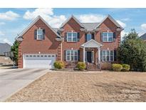 Charming red brick two-story home featuring a two-car garage, manicured lawn, and covered front entry at 5608 Old Town Ln, Gastonia, NC 28056