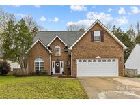 Charming two-story brick home featuring an attached two-car garage, manicured lawn, and inviting front entrance at 4741 Lauren Glen Nw St, Concord, NC 28027