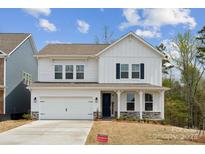 Charming two-story white home featuring stone accents, a two-car garage, and a welcoming front porch at 1439 Hubert Graham Way, Tega Cay, SC 29708