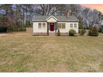 Charming single-story home featuring a red front door, chimney, and well-maintained lawn at 27 Liske Nw Ave, Concord, NC 28027