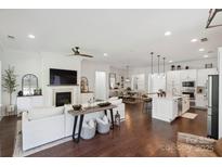 Bright, open-concept living space with hardwood floors, fireplace, and seamless flow to dining and kitchen areas at 4922 Looking Glass Trl, Denver, NC 28037