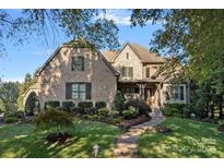 Inviting two-story brick home featuring stone accents and a manicured front yard, exuding curb appeal at 8724 Highgrove St, Charlotte, NC 28277