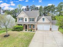 Charming two-story home with neutral siding, stone accents, manicured lawn, and a three car garage at 1122 Hartmann Ct, Fort Mill, SC 29715