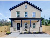 Charming brick home boasts a welcoming front porch, complemented by dark blue accents and meticulous landscaping at 588 Washington Ln, Albemarle, NC 28001