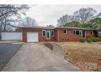 Charming red brick ranch home with driveway, attached garage, separate garage and manicured lawn at 1303 Armstrong Rd, Belmont, NC 28012