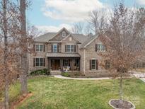 Charming brick home featuring a well-manicured lawn, covered front porch, and beautiful architectural details at 2007 Fernhurst Ter, Matthews, NC 28104