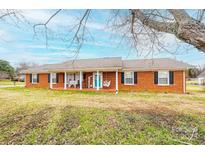 Charming brick home with a cozy front porch featuring a swing and ample seating at 30 Hillsboro Rd, Taylorsville, NC 28681