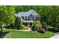 Charming two-story brick home featuring a well-manicured lawn and lush landscaping at 653 Buckleigh Nw Ct, Concord, NC 28027