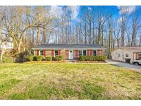 Traditional brick home with red shutters, showcasing a neat front yard and mature trees at 1203 Northwoods Dr, Kings Mountain, NC 28086