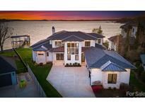 Stunning exterior view of waterfront home highlighting modern design, pristine landscaping, and sunset at 18601 Bluff Point Rd, Cornelius, NC 28031