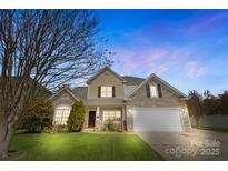 Charming two-story home with a stone and tan exterior and well-manicured lawn at dusk at 1016 Filly Dr, Indian Trail, NC 28079