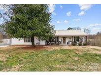 Charming single-story home featuring a metal roof and rocking chair front porch at 24253 Old Aquadale Rd, Albemarle, NC 28001