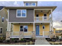 Charming two-story home with a welcoming front porch, stone accents and stylish yellow and gray siding at 283 Luray Way # 449, Rock Hill, SC 29730