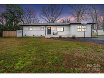 Charming single-story home featuring a well-manicured lawn and classic brick exterior with black trim at 404 Plaza Dr, Harrisburg, NC 28075