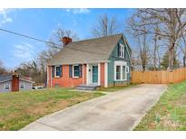 Charming two-story home featuring a brick facade, green siding, and a concrete driveway at 514 3Rd Avenue Se Dr, Hickory, NC 28602