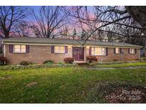 Charming brick home with well-manicured lawn, featuring burgundy shutters and mature landscaping at 9534 Markus Dr, Mint Hill, NC 28227