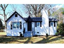 Charming renovated brick home featuring a contrasting black roof and shutters and well maintained yard at 106 Easy St, Concord, NC 28027