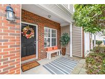 Cozy front porch featuring a brick facade, decorative wreath, and a striped rug over the concrete at 130 Clydesdale Ct, Matthews, NC 28104