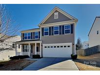 Charming two-story home featuring gray siding, black shutters, a covered porch, and a two-car garage at 242 Elrosa Rd, Mooresville, NC 28115