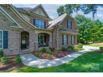 Charming two-story home featuring stone accents, brick, manicured landscaping, and a welcoming front porch at 303 Ridge Reserve Dr # 29, Clover, SC 29710
