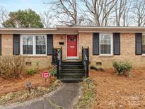 Charming brick home featuring a bright red door, black shutters, and a well-manicured front yard at 3350 Bonneville Dr, Charlotte, NC 28205