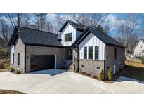 Beautiful new construction home with a gray brick facade, black trim, and a spacious concrete driveway at 4060 Steve Ikerd Ne Dr, Hickory, NC 28601