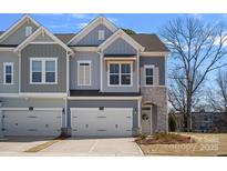 Charming home featuring a stone archway, attached two-car garage, and manicured landscaping at 8233 Houser St, Cornelius, NC 28031
