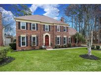 Charming two-story brick home with manicured lawn, dark shutters, and mature trees on a sunny day at 10914 Ridge Acres Rd, Charlotte, NC 28214