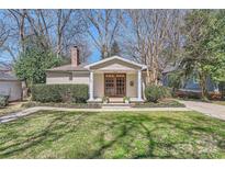 Charming home featuring a cozy front porch with elegant pillars, manicured landscaping, and a well-maintained lawn at 1409 Cortland W Rd, Charlotte, NC 28209