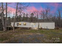 Cozy single-story home featuring a long layout and wooded surroundings during the daytime under pink clouds at 144 Cherokee Ln, New London, NC 28127