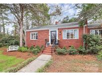 Charming red brick home with black door, white trim, and landscaped front yard and brick walkway at 1817 Jameston Dr, Charlotte, NC 28209