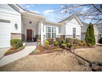 Charming home featuring a brick accent wall, colorful landscaping, and a lovely red front door at 5306 Tilley Manor Dr, Matthews, NC 28105