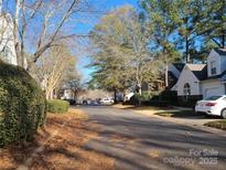 Neighborhood street view with mature trees and well-maintained landscaping under a bright blue sky at 5963 Moose Ln, Charlotte, NC 28269