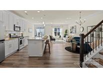 Open-concept living room features hardwood floors and flows into a modern kitchen with stainless steel appliances at 6450 Keeton Ln, Harrisburg, NC 28075
