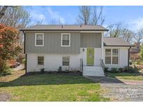 Inviting two-story home featuring gray and white brick exterior, lush landscaping, and a bright green front door at 6914 Idlewild Rd, Charlotte, NC 28212